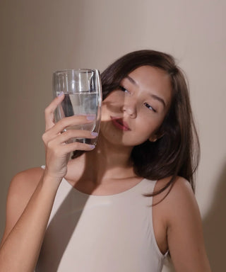 femme regarde verre de complément alimentaire antioxydant hodygé avec le sourire