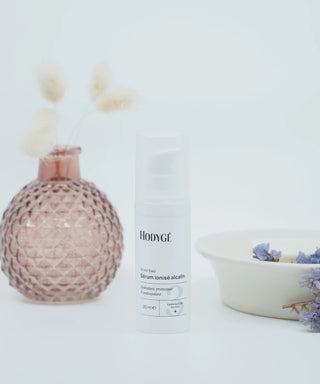 le sérum Hodygé au centre un pot de fleur rose à gauche et un porte savon beige à droite